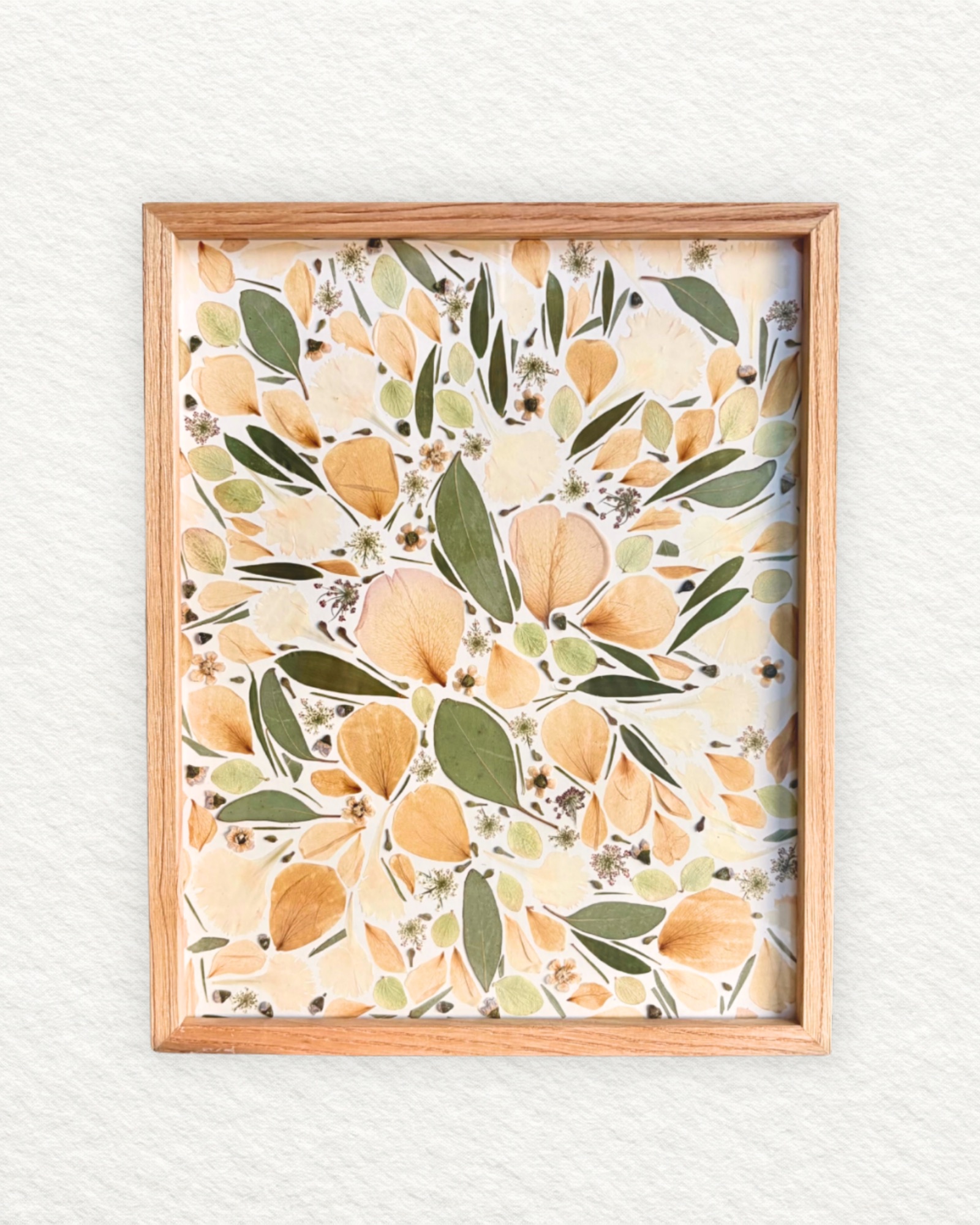 Bouquet de mariée pressé aux pétales pêche et feuilles vert olive, encadré en bois clair, petit format